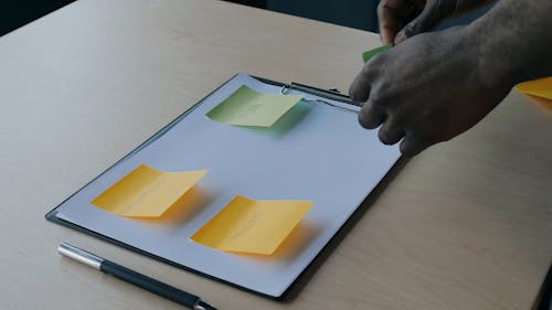 Close-Up View of Person Sticking Notes on a Paper