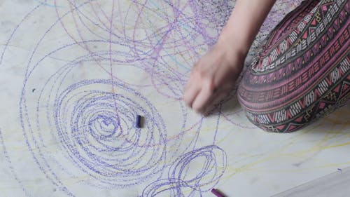 Female Artist Drawing With Crayon on Floor