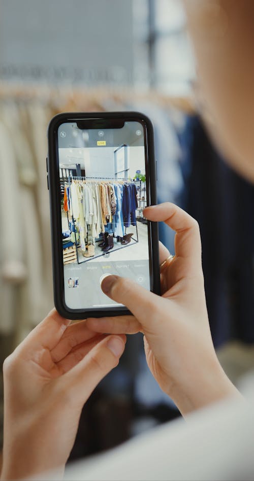 A Person Taking Picture of Clothes in a Rack
