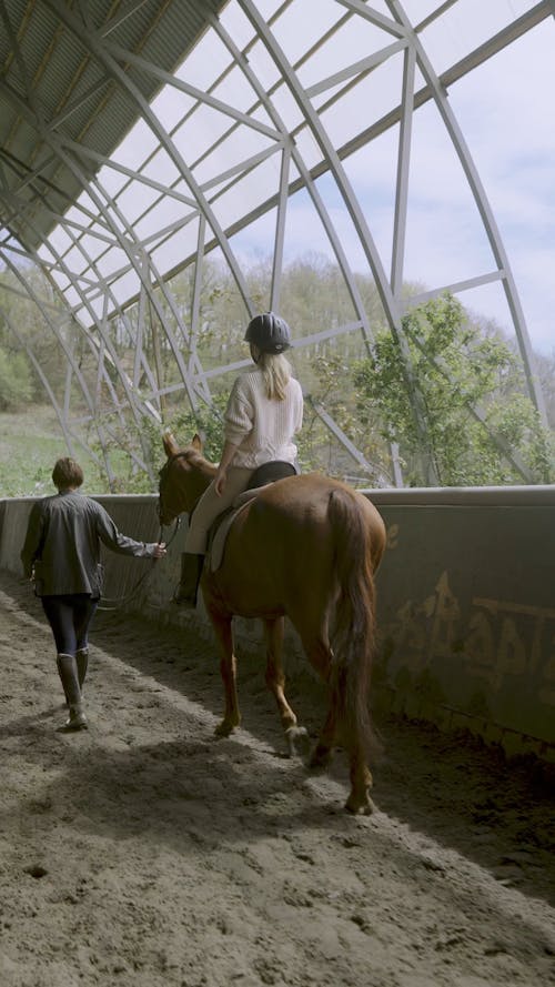 A Person Guiding a Woman while Riding a Horse