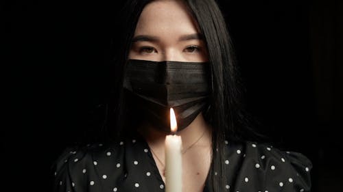 Woman Wearing Facemask In Front of a Candle