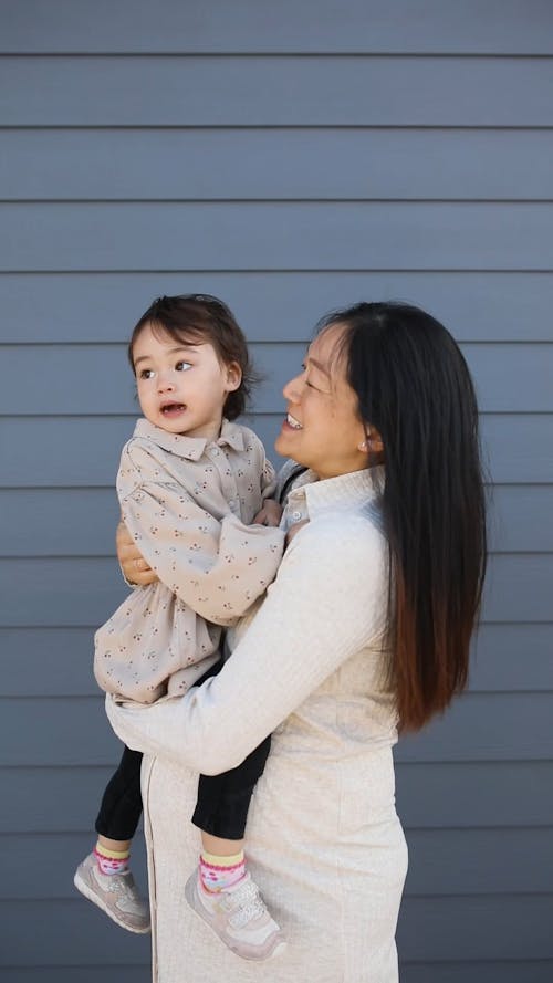 Mother And Child Standing Near A Gray Wall