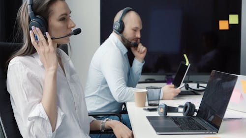 Call Center Agents Talking to Customers while using Cellphone and Laptop