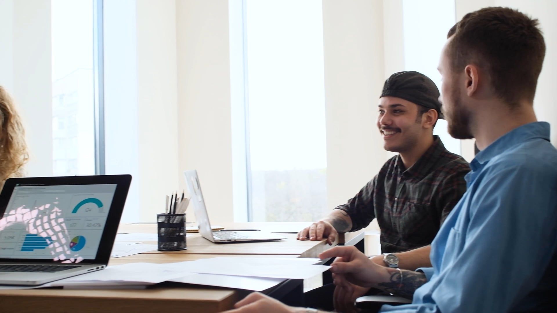 Colleagues collaborating around a laptop in a bright office