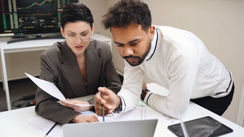 A Man and A Woman Looking at a Laptop While Talking
