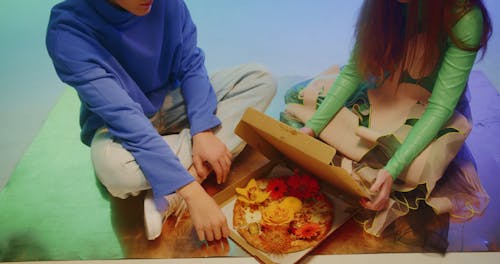A Couple Opening a Box of Pizza with Flowers