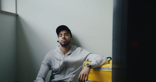 A Delivery Man Sitting Beside a Thermal Bag