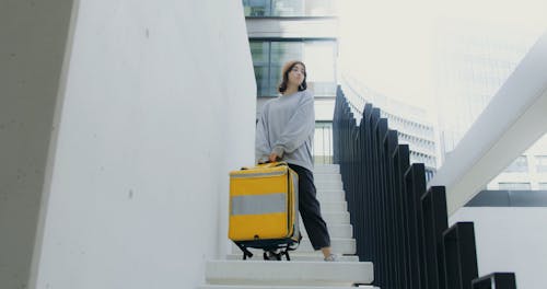 Woman Carrying a Thermal Bag Standing on the Staircase