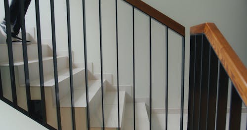 A Delivery Man Going Down the Stair while Carrying a Thermal Bag