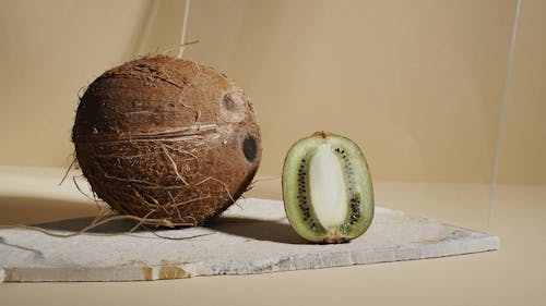 A Coconut and a Sliced Kiwi With a Rolling Ball Made of Wood