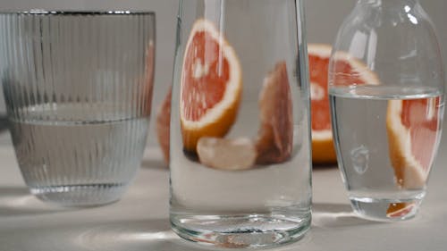 Close Up View of Sliced Grapefruits and a Crystal Behind Glasses of Water