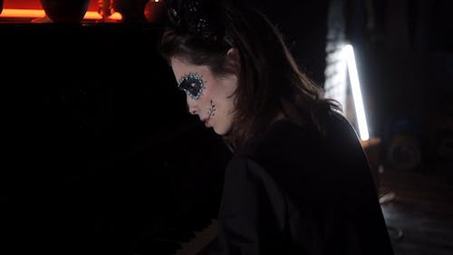A Woman with a Creepy Makeup Playing a Piano