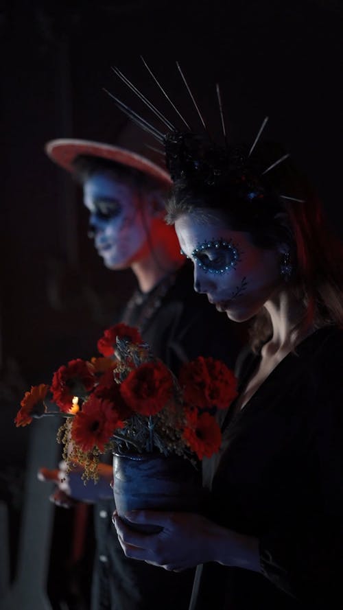 A Couple with Face Painting Offering Candle and Flowers