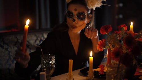 A Woman with a Creepy Makeup Lighting a Candle