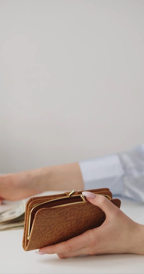 A Person Putting Money Inside a Wallet