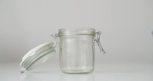 A Person Putting a Roll of Money in a Glass Jar