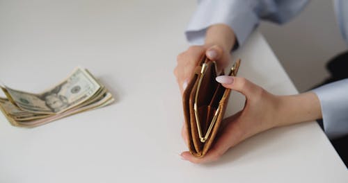 A Person Putting Money Inside a Wallet