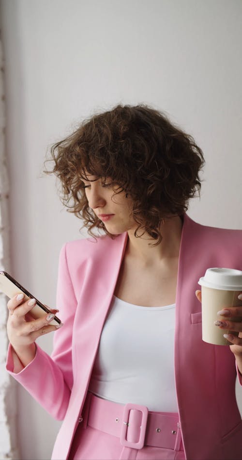 A Woman Drinking Coffee while Using Her Cellphone