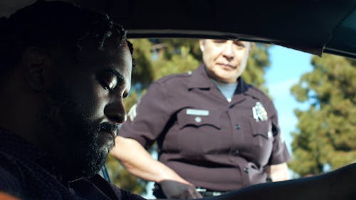 A Police Officer Talking to a Man Inside the Car