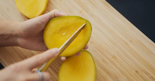 A Person Slicing a Mango Fruit