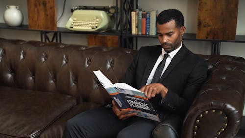 A Man Reading a Book on the Couch