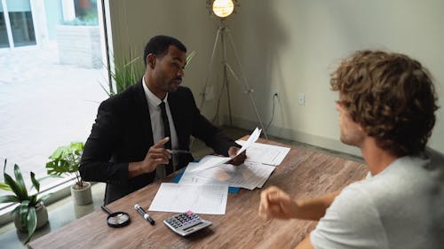 An Agent Talking to His Client while Holding Documents