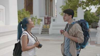 woman holding a camera talking to a man