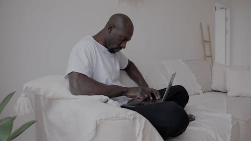 Man Sitting on Sofa Using a Laptop