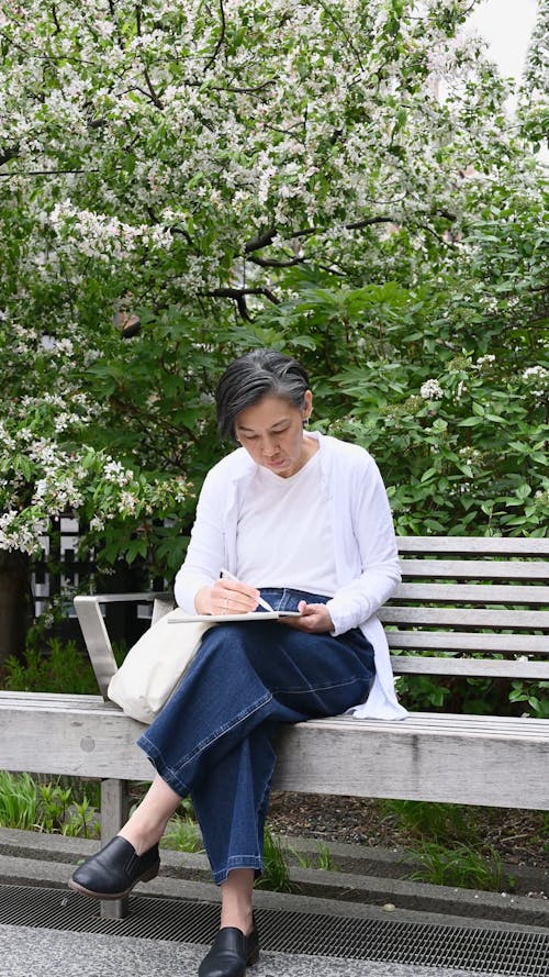 A Woman Sitting on a Bench while Writing