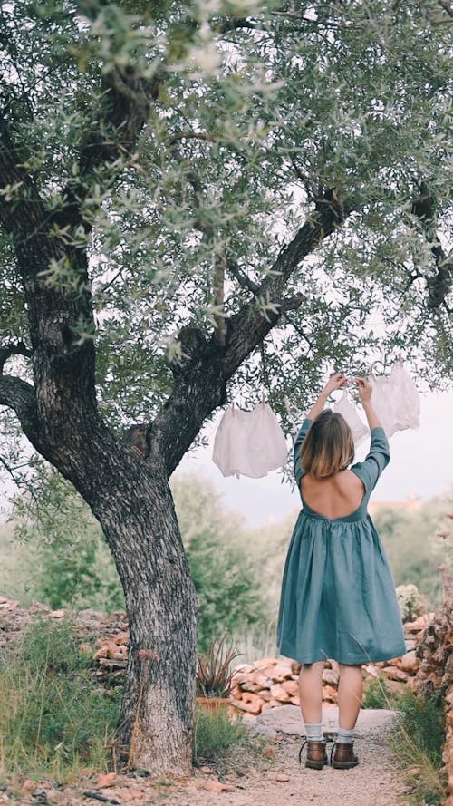 Young Woman Hanging Clothes on Tree