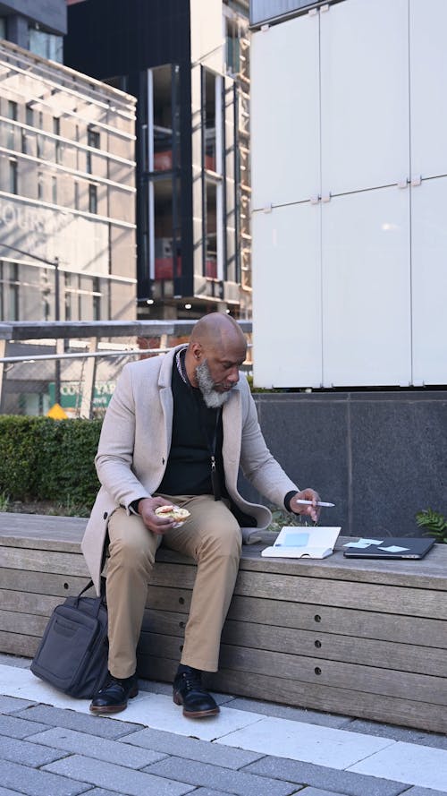 A Man Taking Notes while Holding a Sandwich