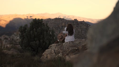 A Woman Sitting on a Rock Formation while Looking at the View