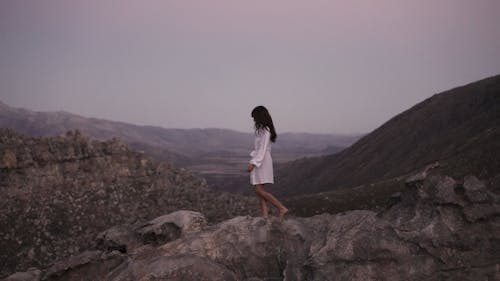 A Woman Standing on a Rock Formation while Looking at the View