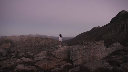 A Woman Standing on a Rock Formation while Looking at the View