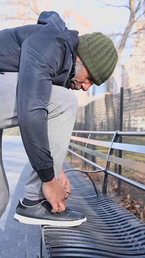 A Man Tying his Shoelaces on a Bench