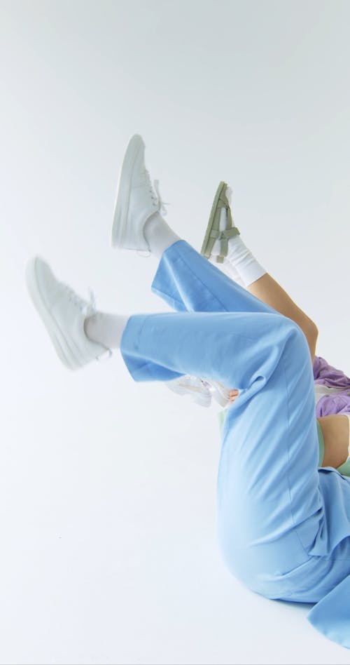 Young Women Moving Their Feet while Lying Down on the Floor