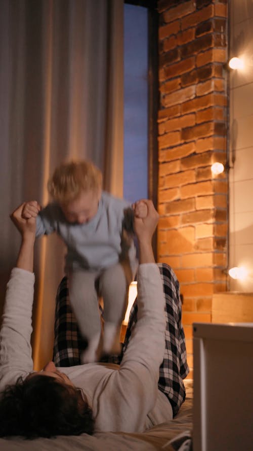 A Father is Playing with His Son in the Bed