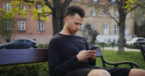 A Man Using Smartphone while Sitting on a Bench
