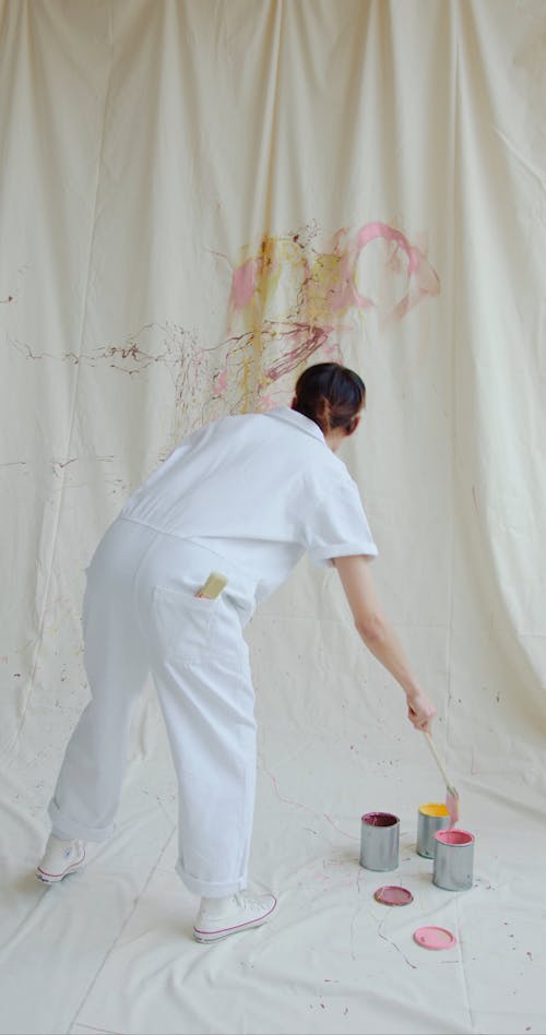 Backview of a Man Splattering Paint on a Canvas