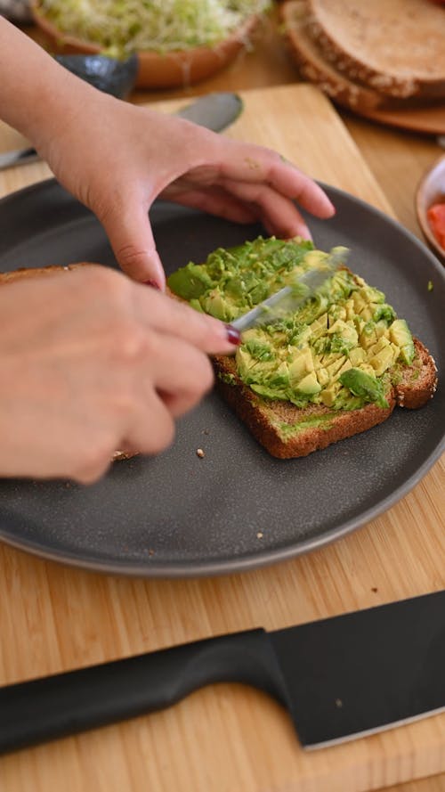 Person Mashing Avocado on Bread