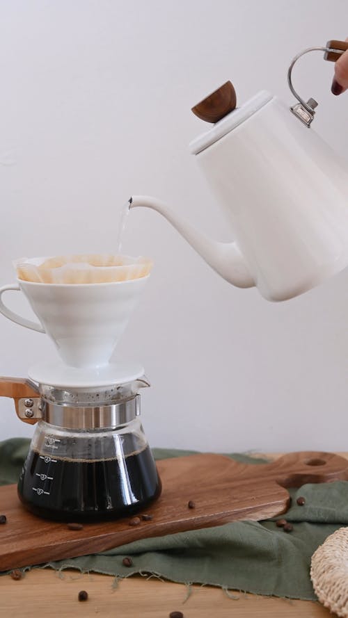 A Person Pouring Hot Water In A Coffee Filter Cup