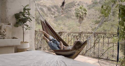 A Woman Resting in the Hammock of the Balcony
