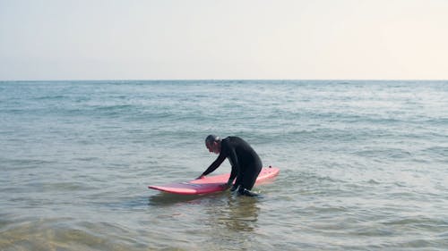 Surfer Carrying is Surfboard Out the Water