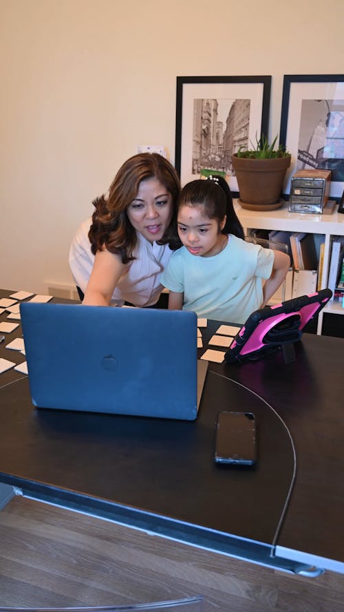 A Woman Using a Laptop with her Daughter