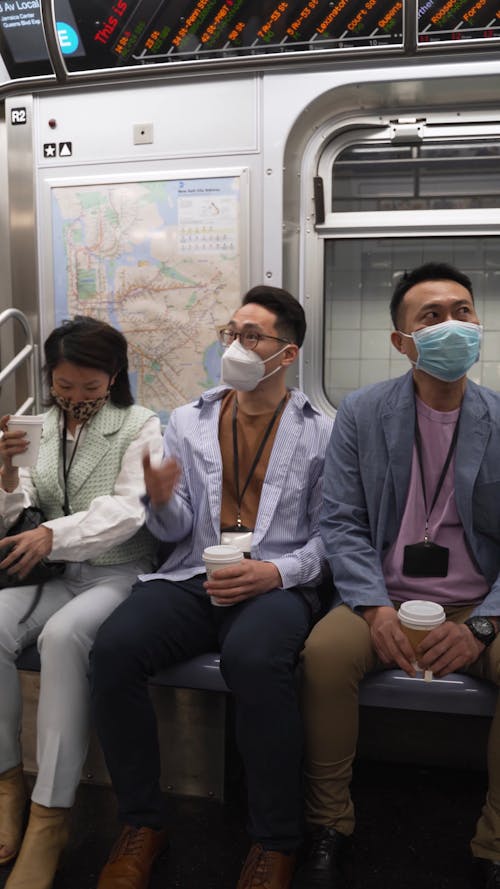Two Men And Woman Sitting Inside A Train With Face Masks