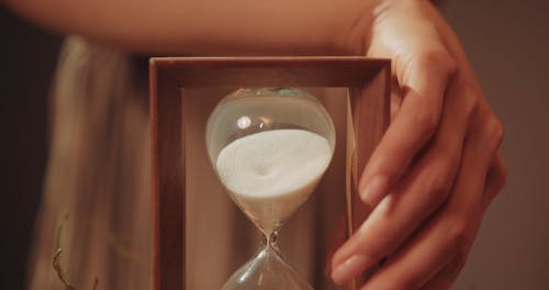 A Hand Turning Over an Hourglass