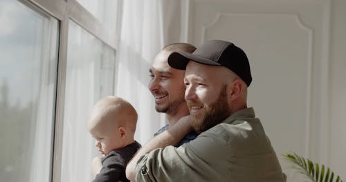 A Couple Looking Outside a Window while Holding a Baby