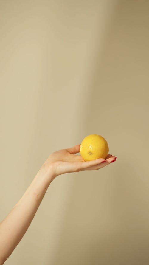 Female Hand Holding Yellow Fruit