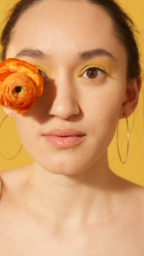 Woman With Yellow Makeup Holding a Flower