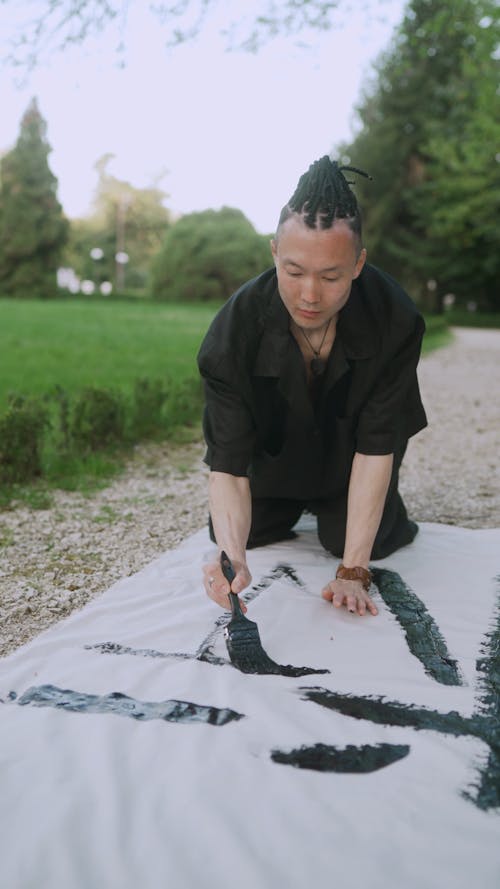 Man Painting Japanese Characters On White Textile